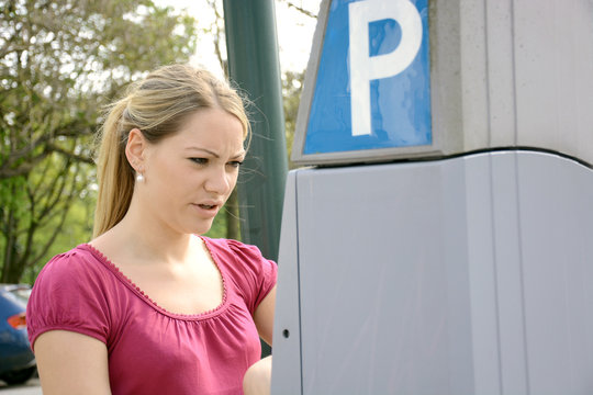 Junge Frau hat Probleme mit Parkscheinautomaten