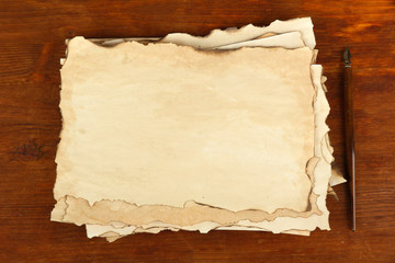 Old paper and ink pen on wooden background