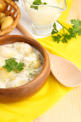 Tender young potatoes with sour cream and herbs in wooden bowl