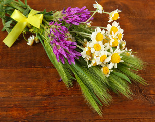Wild flowers and green spikelets, on wooden background