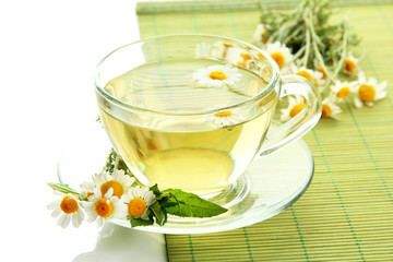 Cup of herbal tea with wild camomiles and mint, isolated
