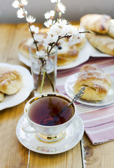 Blossoming apricot in the glass, cup of tea and puffs.