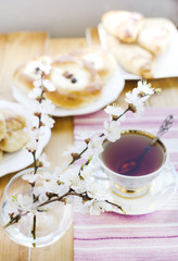 Blossoming apricot in the glass, cup of tea and puffs.