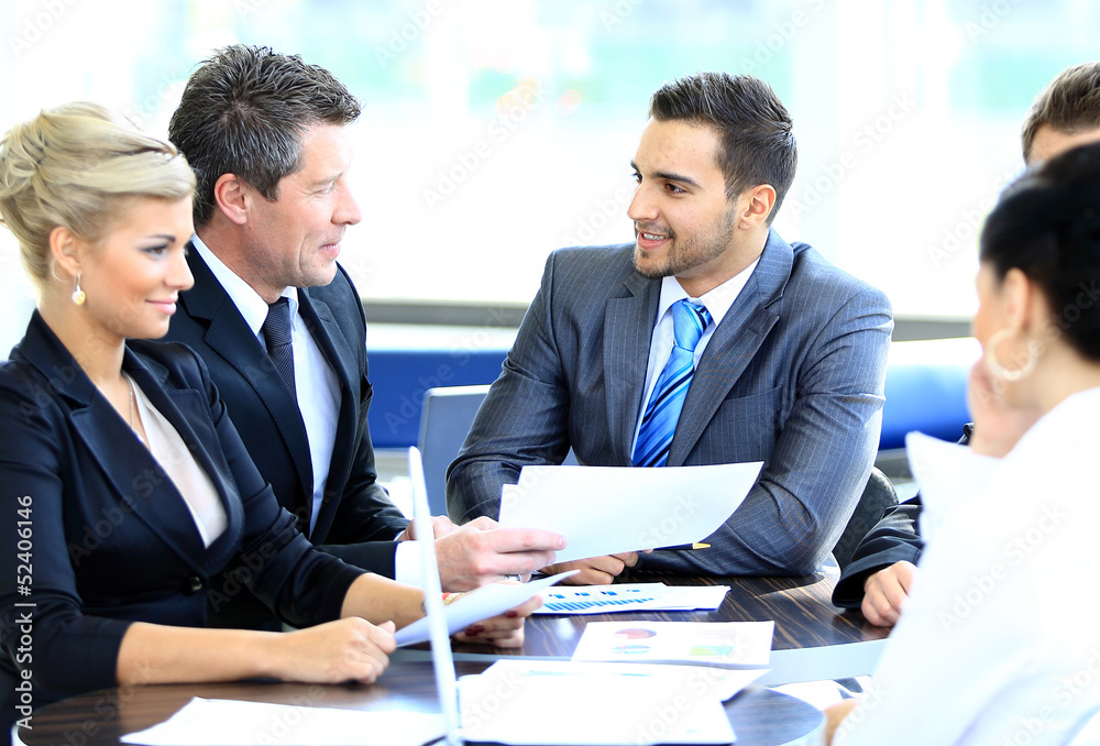 Wall mural smiling young man sitting at a business meeting with colleagues