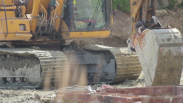 Construction extravator diggin in the ground. People in the shot