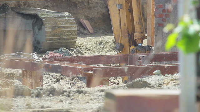 Construction extravator diggin in the ground. People in the shot