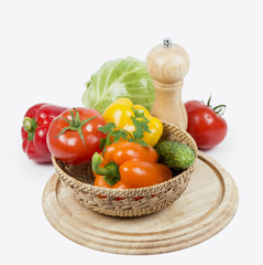 Fresh vegetables, wooden chopping board, white background.