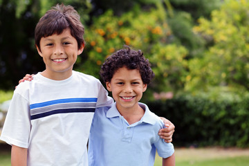 Two smiling happy young mixed race boys outside