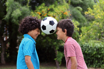 Two young boys playng with a soccer ball