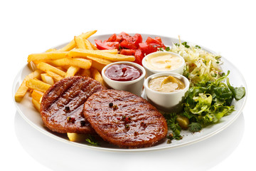 Grilled steaks, French fries and vegetables