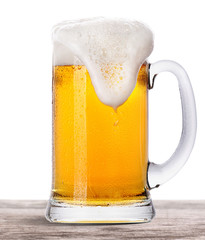 Frosty fresh beer  with foam isolated  on wooden table