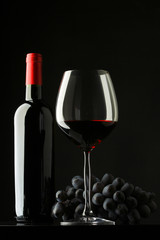 bottle with red wine and glass and grapes