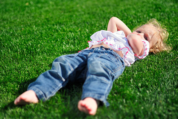 Baby girl laying on the green grass in the park