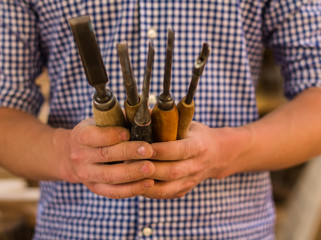 Man is holding a chisel on wood