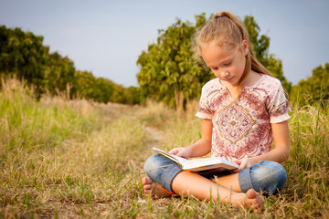little girl sitting and reading a book on nature