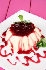 Panna Cotta with raspberry sauce, on color wooden background