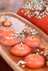 Beautiful candles in water on wooden table close-up