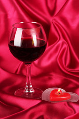 Glass of wine with lipstick imprint on red fabric background