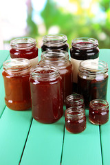 Tasty jam in banks on table on bright background