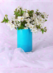 Obraz premium Flowering branches in vase on light fabric background
