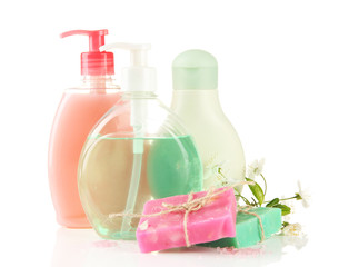 Cosmetics bottles and natural handmade soap on green background