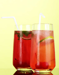 Two cherry cocktails with ice on green background