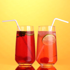 Two cherry cocktails with ice on orange background