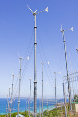 Series of wind power generators in clear blue sky background.