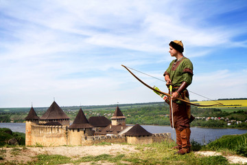 Medieval archer with bow and arrows on castle background