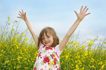 Naklejka na ściany i meble happy little girl on a field with flowering colza
