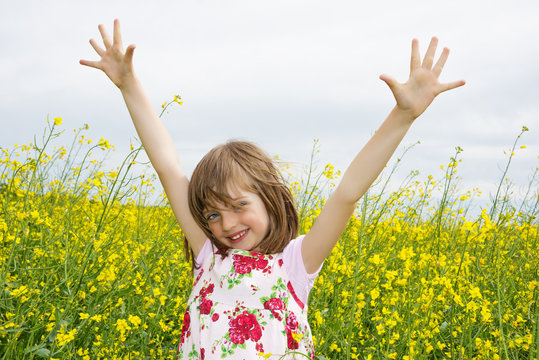 happy little girl on a field with colza