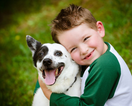 Child lovingly embraces his pet dog, a blue heeler