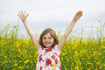 Naklejka na ściany i meble happy little girl on a field with rapeseed