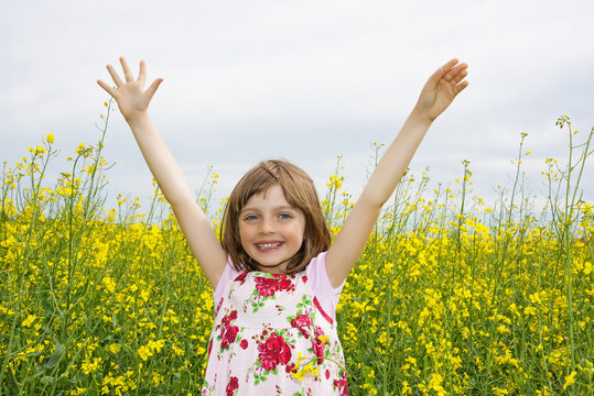 happy little girl on a field with rapeseed