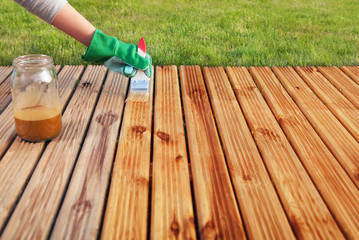 Applying protective varnish on a patio wooden floor - 52435982