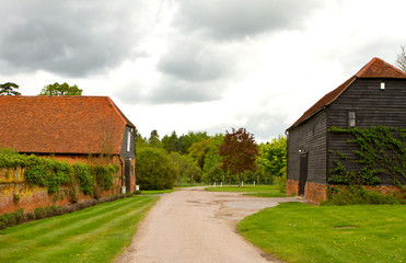 Farm and outbuildings in an English countryside scene on a storm