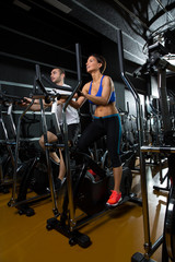 Fototapeta na wymiar elliptical walker trainer man and woman at black gym