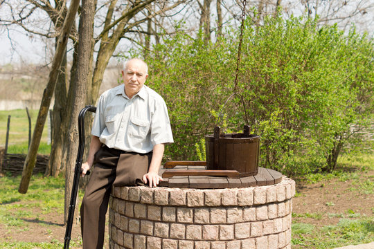 One legged man sitting on an old well