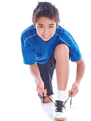 Junge bindet die Schnürsenkel seiner Sportschuhe