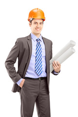 Young male architect wearing helmet and holding blueprints