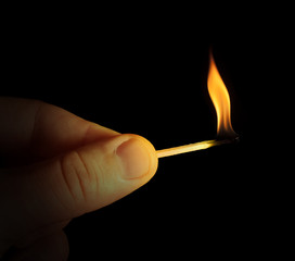 Hand holding burning match stick