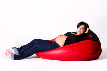 Fototapeta na wymiar Pregnant woman on a red sako pillow