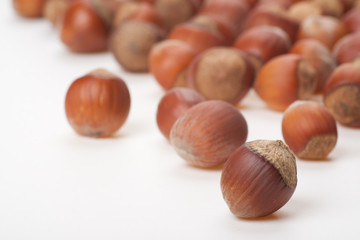 Unbroken hazelnuts on white surface