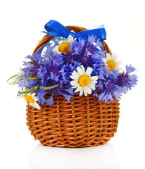 Beautiful bouquet of cornflowers and chamomiles in basket,