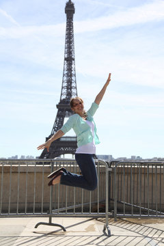 Happy young woman jumping aganist Eiffel Tower