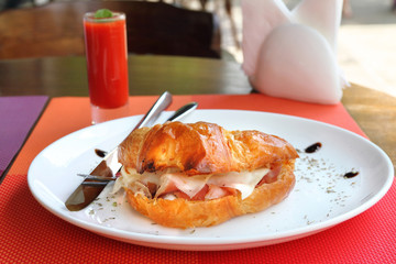 Croissant sandwich with parma ham, cheddar cheese and eggs