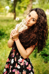 Portrait of young beautiful woman with a dandelion