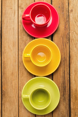 Colorful coffee cups and plates over wooden background