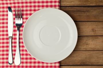 Empty plate with fork and knife on tablecloth