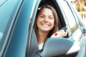 Smiling girl sitting in a car and showing key